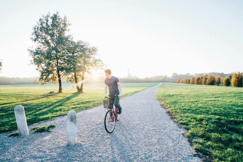 Hombre paseando por el parque con su bicicleta